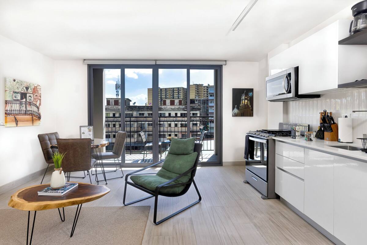 A modern apartment with a balcony, a dining area, and a kitchen.