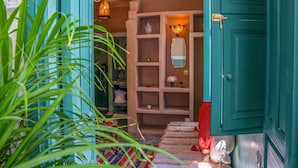 A hallway with teal doors, a staircase, and a shelf with decorative items. - Riad Dada Messouda & spa (Marrakech)