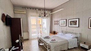 Quarto com cama, mesa de cabeceira e uma cadeira. Um candelabro pendurado no teto.