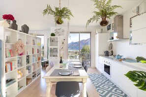 Een moderne keuken met een eethoek, grote ramen en uitzicht op bergen.