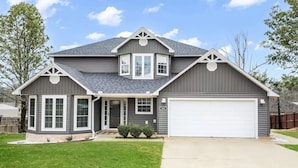A two-story house with a garage, a covered front porch, and a well-maintained lawn. - Lake Hamilton Carriage House, 5 bed, 3.5 bath, Sleeps 17, Game rm, pet friendly! (Hot Springs)