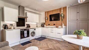 Une cuisine moderne dotée d’appareils électroménagers intégrés, un coin repas avec une table en marbre et un espace salon confortable.
