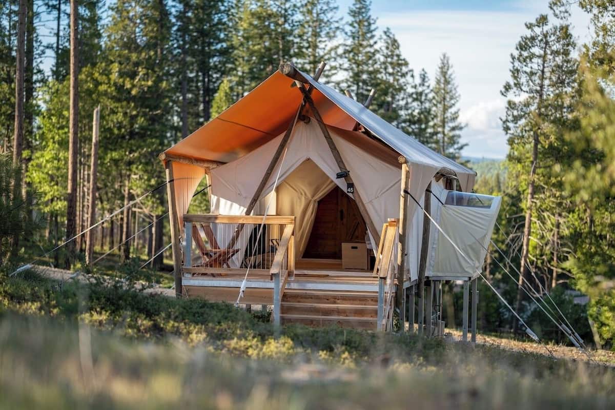 A tent with a wooden deck, a chair, and a small table.