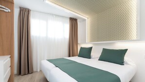 A neatly made bed with green bedding, a wooden wardrobe, and a large window with sheer curtains. - Alsol Los Caribes 2 (San Bartolomé de Tirajana)