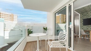 A balcony with a glass railing, a white table, and two white chairs. - Alsol Los Caribes 2 (San Bartolomé de Tirajana)