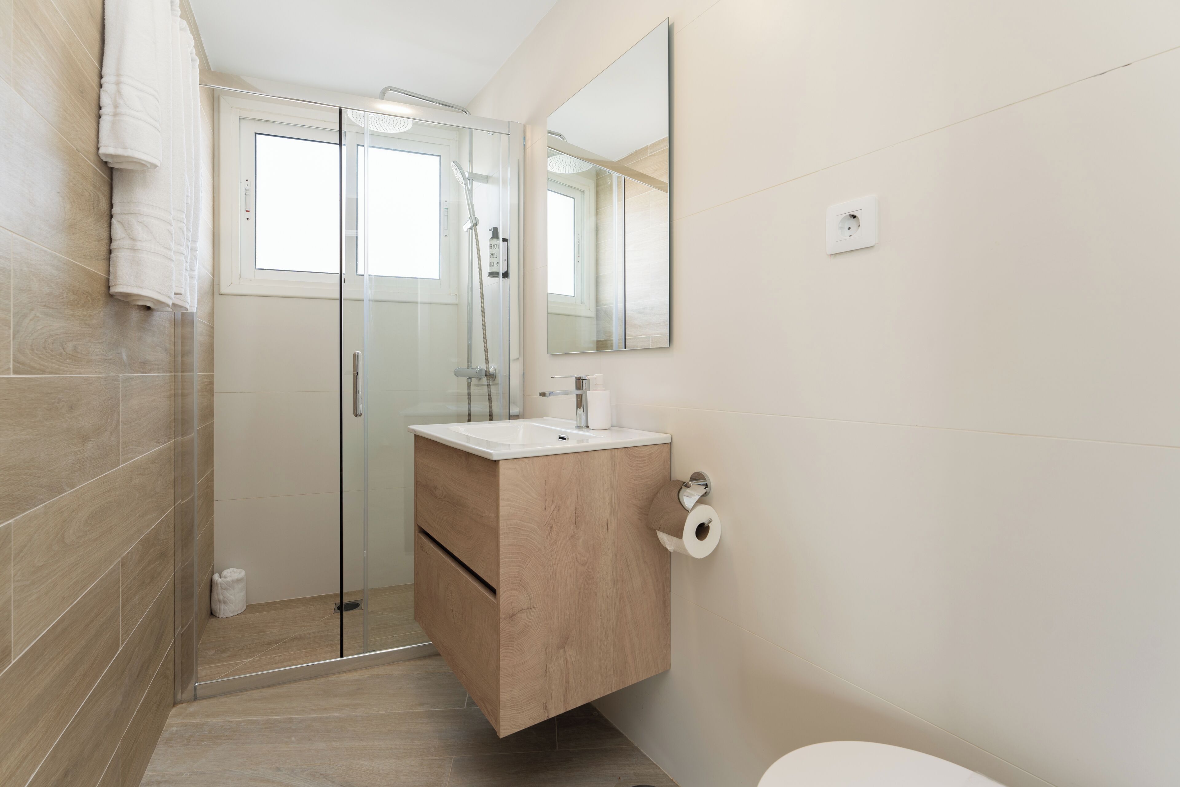 Une salle de bain moderne avec une douche à parois de verre, un meuble-lavabo en bois et des toilettes.