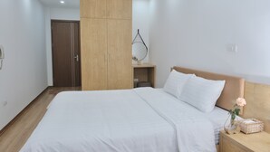 A bedroom with a large bed, wooden wardrobe, bedside table, and a small bedside lamp. - HONEYMOON HOTEL 2 (Hanoi)