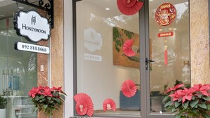A hotel entrance with a sign reading "Honeymoon," a phone number, and decorative red fans and plants. - HONEYMOON HOTEL 2 (Hanoi)