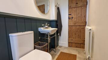 A bathroom with a white toilet, a white sink, a wooden door, and a radiator.