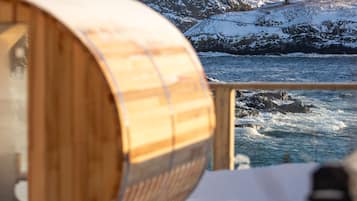 Una botte di legno, una ringhiera e un litorale roccioso con neve.
