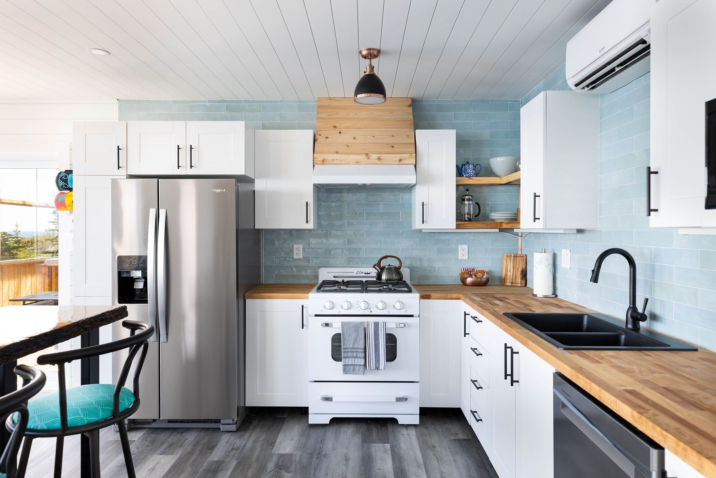A compact kitchen with white cabinets, a stainless steel refrigerator, a gas stove, and a dishwasher.