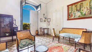 A room with a checkered floor, a large painting on the wall, and a door leading outside. - Villa Donna Linda by BarbarHouse (Taviano)