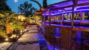 Uma área de bar com pergolado de madeira e assentos.