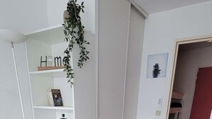 En moderne stue med en hvid sofa, et lille hvidt bord og en reol.