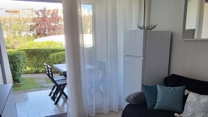 En moderne stue med en sort sofa, et spisebord med stole, og en skydedør, der fører ud til en patio.