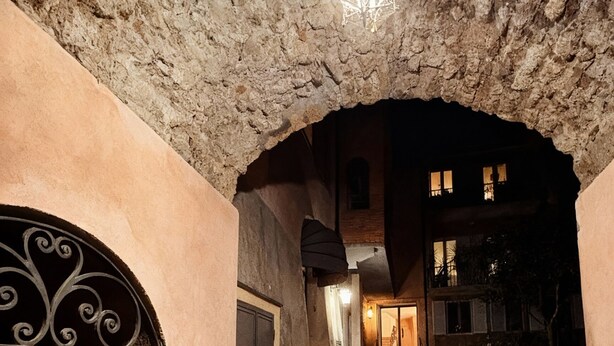 Una escala de pedra que porta a l'entrada d'un edifici, amb una reixa de metall i un fanal a la part superior.