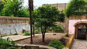 Un pati amb parets de pedra, una banca i plantes en testos.
