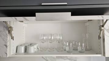 Eine Küche mit Marmorarbeitsplatte, einem weißen Schrank mit Schublade sowie verschiedenen Gläsern und Tassen.