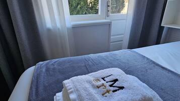 Habitación de hotel con una cama, ventana con cortinas y vistas a zonas verdes.