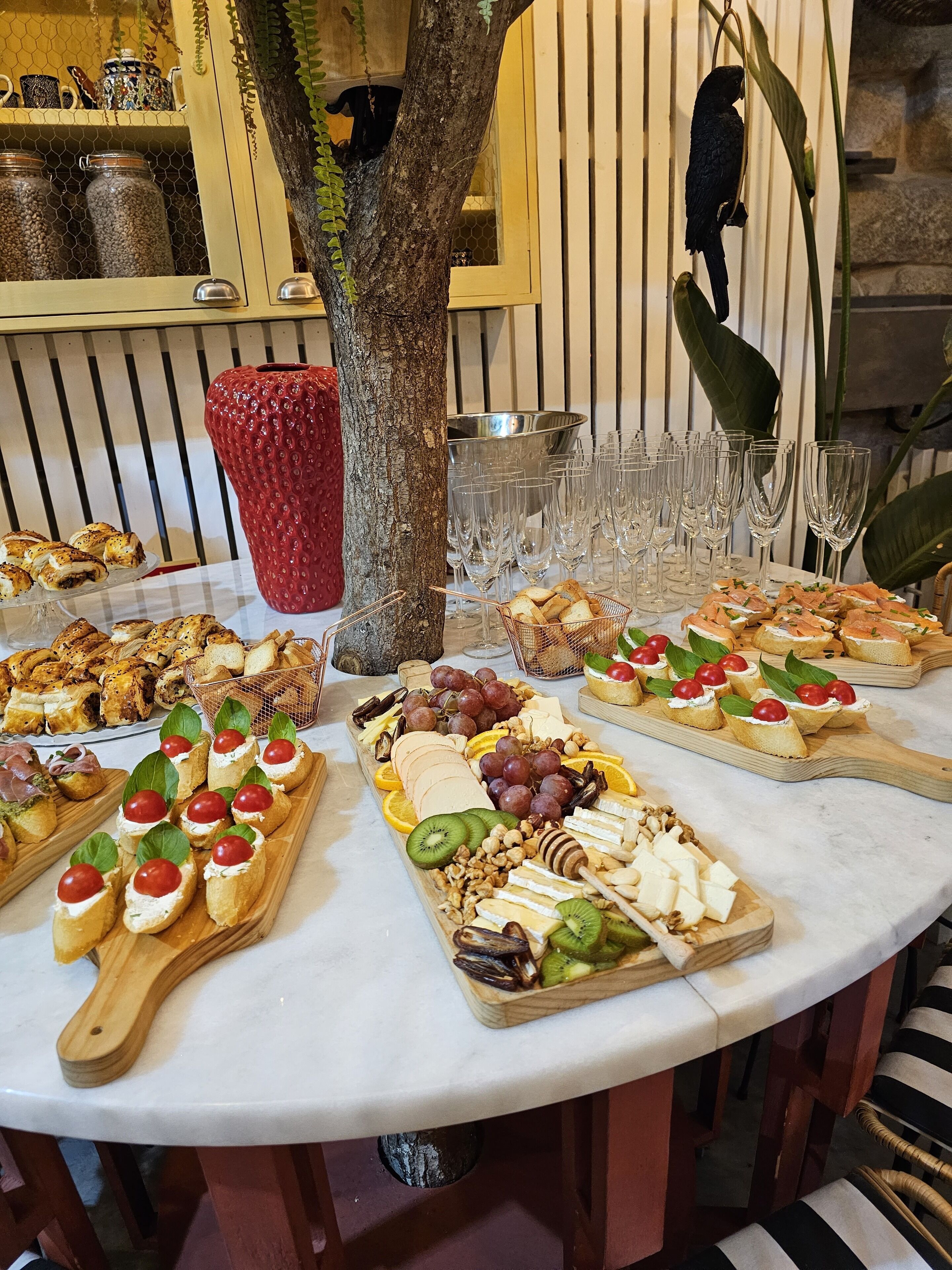 Una mesa redonda con diferentes bandejas de comida, incluyendo canapés, quesos y frutas.