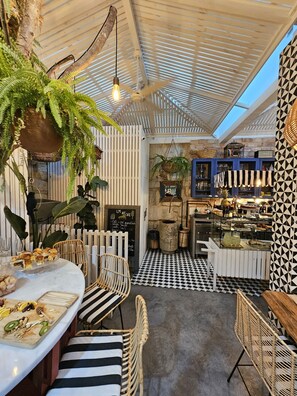 A cafe with a checkered floor, hanging plants, and wicker furniture. - LM Art Apartments (Porto)