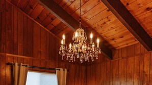 Une chambre aux murs lambrissés, dotée d’un lit à baldaquin, d’un lustre et d’une fenêtre avec des rideaux.