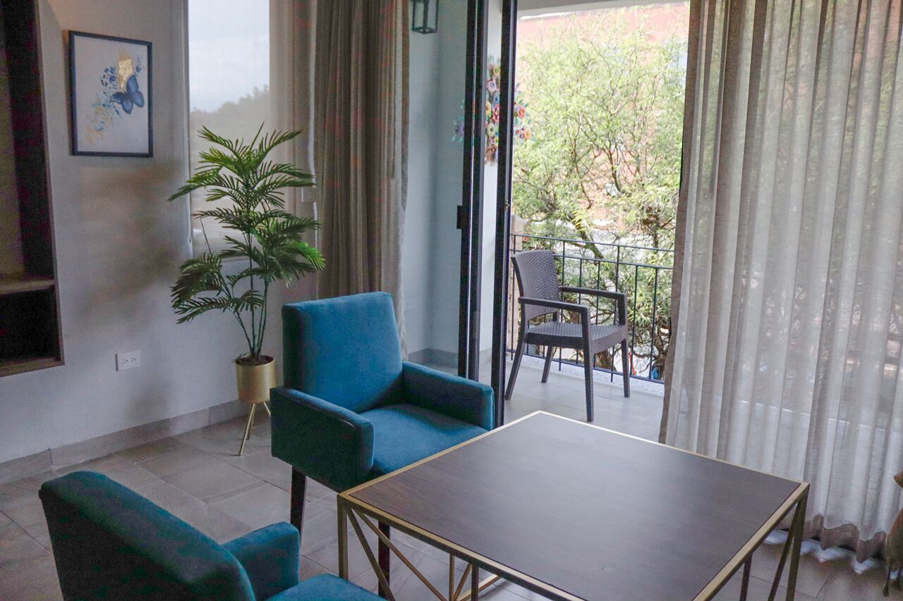 Una habitación con una mesa, dos sillas, una planta en maceta y vistas a un balcón con una silla y una mesa.