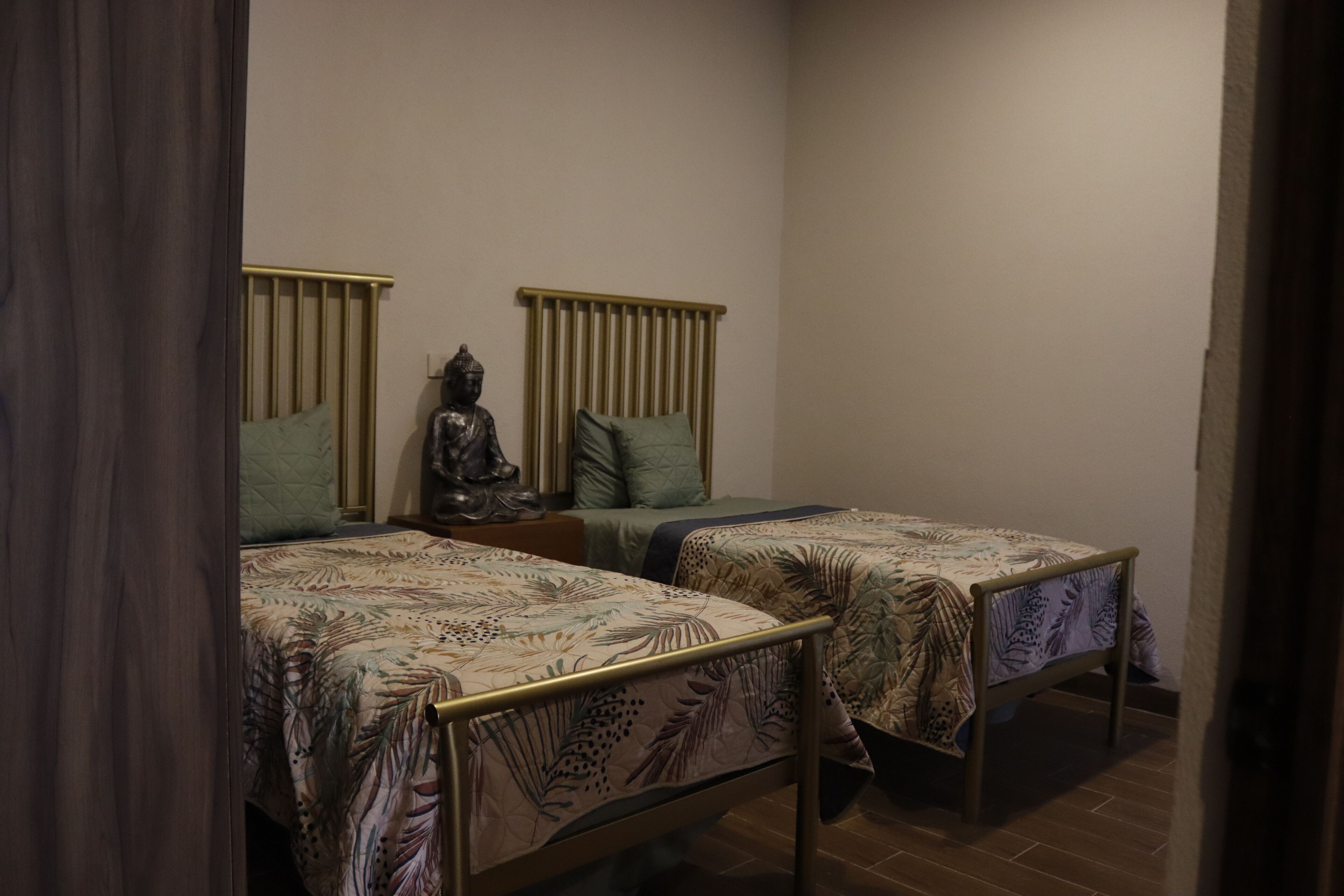 Een slaapkamer met twee eenpersoonsbedden, elk met hoofdbord en kussen.