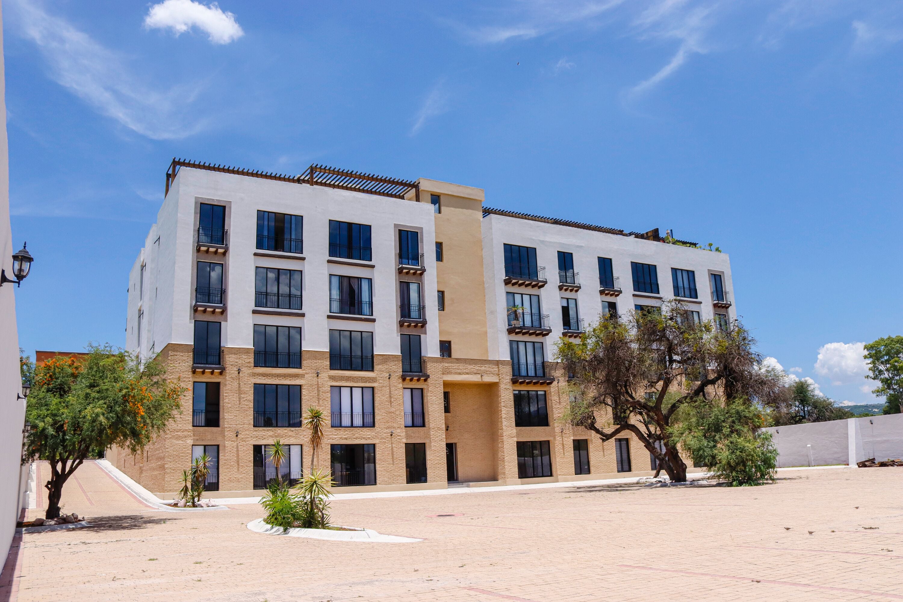Un edificio a più piani con tetto piatto, ampie finestre e un cortile lastricato.