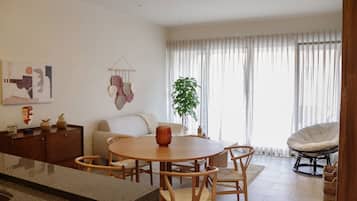 Un salon moderne avec une table ronde en bois, un canapé, un fauteuil et une plante en pot.