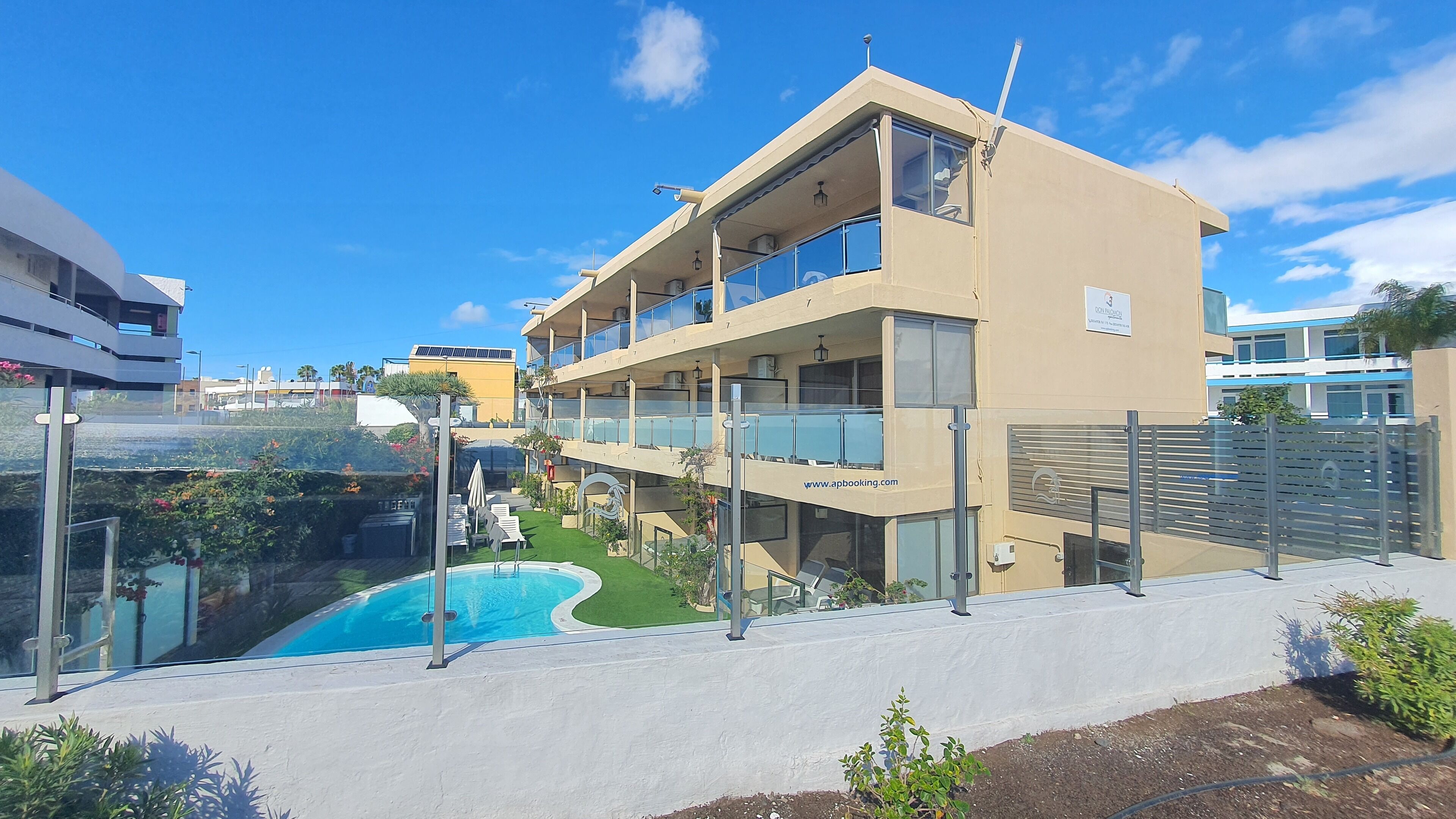 A modern building with a pool, balconies, and a website URL.