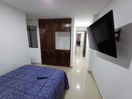 Un dormitorio con cama, armario y televisor montado en la pared.
