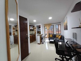 Amplia sala de estar con sofá, una mesa de comedor y cocina al fondo.