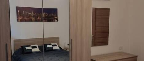 A bedroom with a bed, a wardrobe, a dresser, and a painting on the wall.