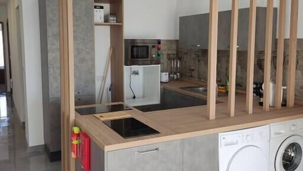 Uma cozinha moderna com micro-ondas, fogão e máquina de lavar embutidos.