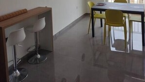 Quarto moderno e bem iluminado com uma mesa de jantar e cadeiras, um aparelho de ar condicionado e uma grande janela com vista para edifícios.