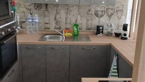 Uma cozinha moderna com armários cinzentos, micro-ondas, pia e bancada com diversos objetos.