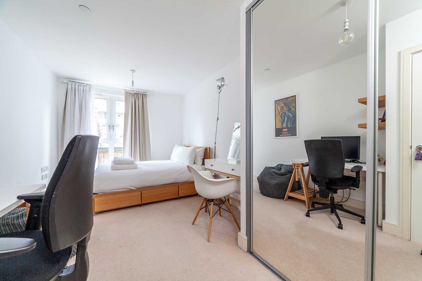 Una habitación de hotel moderna con cama, escritorio, silla y ordenador.