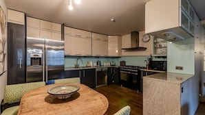 Una cocina moderna con una isla central, electrodomésticos de acero inoxidable y un comedor con mesa de madera y sillas estampadas.