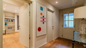 Un pasillo con una estantería, una puerta decorativa y una lámpara.