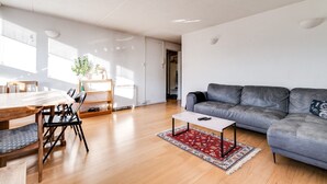 A modern living room with a grey sofa, wooden dining table, and chairs. - Cosy Battersea Flat (London)