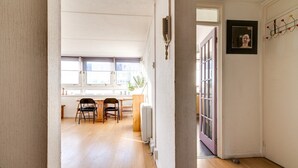 A hallway leading to a dining area with wooden flooring, a radiator, and a door with a glass panel. - Cosy Battersea Flat (London)