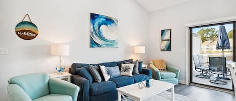 Ein modernes Wohnzimmer mit einer Couch, Sesseln, einem Couchtisch und Kunstwerken an den Wänden.