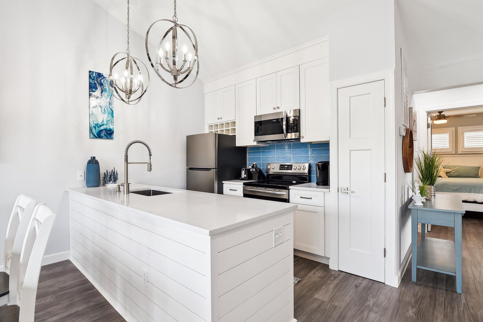 A modern kitchen with white cabinetry, stainless steel appliances, and a central island.