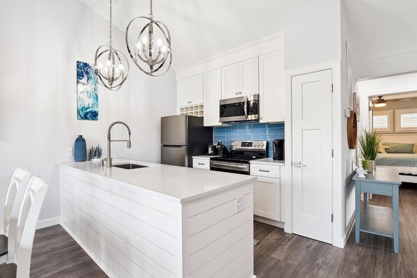 A modern kitchen with white cabinetry, stainless steel appliances, and a central island.