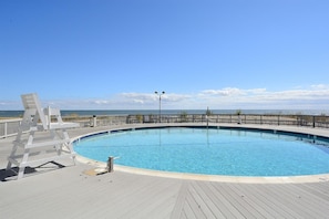 Une piscine circulaire dotée d’une terrasse en bois et offrant une vue sur l’océan.