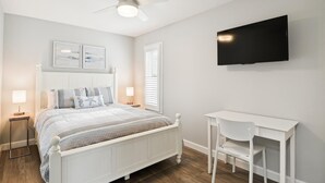 A bedroom with a bed, bedside tables, a desk, a chair, a ceiling fan, and a TV. - Lakefront Sea Colony Villa! Amenity Rich with Private Beach and Shuttle! (Bethany Beach)