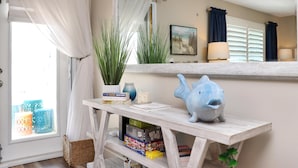 A room with a white console table, a blue fish sculpture, a potted plant, and a mirror reflecting the room. - The Blue Pearl (Port St. Joe)