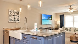 A kitchen with a marble island, blue cabinets, and pendant lighting. - The Blue Pearl (Port St. Joe)