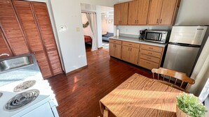 A modern kitchen with wooden cabinets, a stainless steel refrigerator, a microwave, and a sink. - Oak Street Station in Downtown Mahomet (Mahomet)